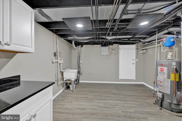 basement with light hardwood / wood-style floors, gas water heater, and sink