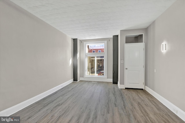 unfurnished room featuring light wood-type flooring and a textured ceiling