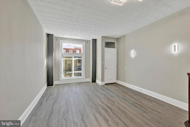 spare room with a textured ceiling and light hardwood / wood-style flooring