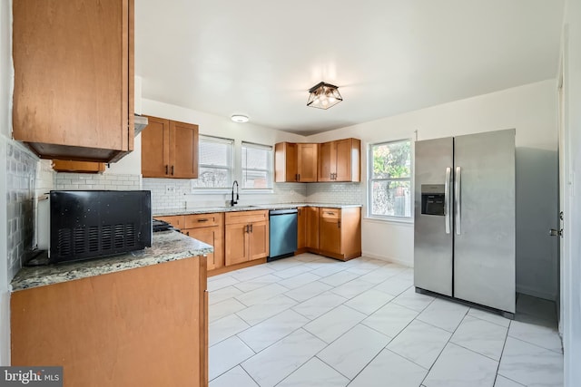 kitchen featuring decorative backsplash, stainless steel appliances, light stone counters, and sink