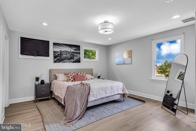 bedroom with multiple windows and hardwood / wood-style flooring