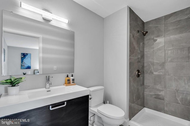 bathroom featuring vanity, toilet, and tiled shower