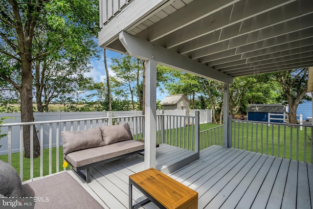 deck featuring an outdoor living space, a lawn, and a storage shed