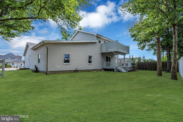 rear view of house featuring a lawn and a balcony