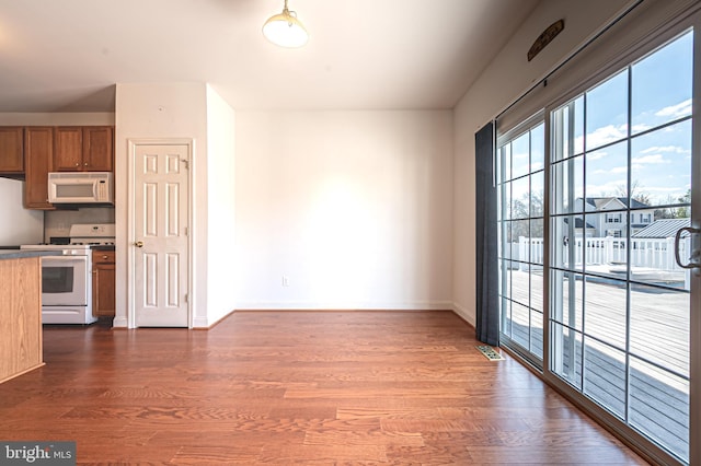 interior space featuring brown cabinets, visible vents, dark wood-type flooring, white appliances, and baseboards