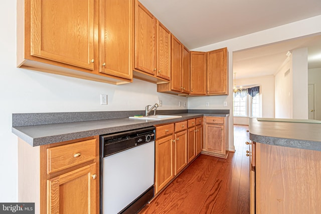 kitchen featuring dark wood finished floors, dishwasher, dark countertops, and a sink