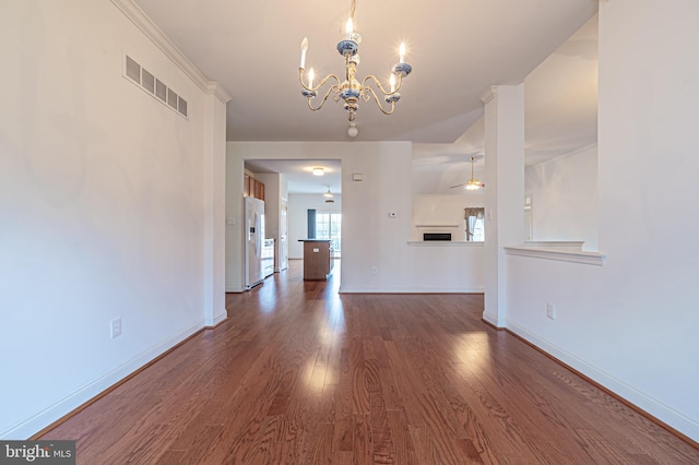 unfurnished living room featuring ceiling fan with notable chandelier, dark wood finished floors, visible vents, and baseboards