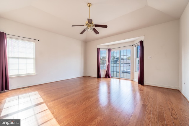 empty room featuring a ceiling fan, visible vents, baseboards, and wood finished floors