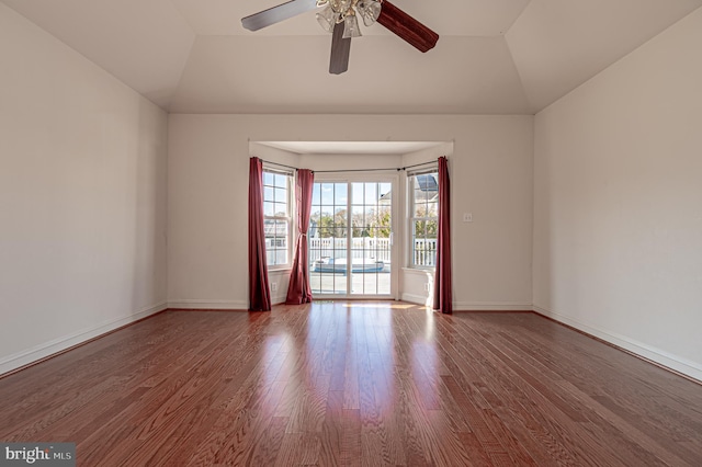 empty room featuring baseboards, vaulted ceiling, and wood finished floors