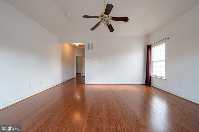 spare room with a tray ceiling, visible vents, ceiling fan, wood finished floors, and baseboards