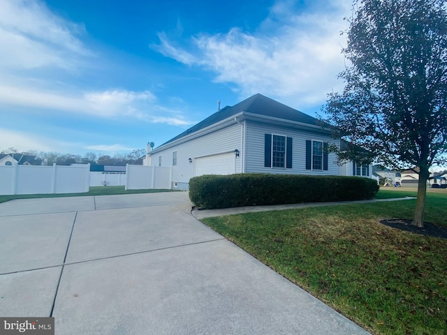 view of side of home featuring driveway, an attached garage, fence, and a lawn