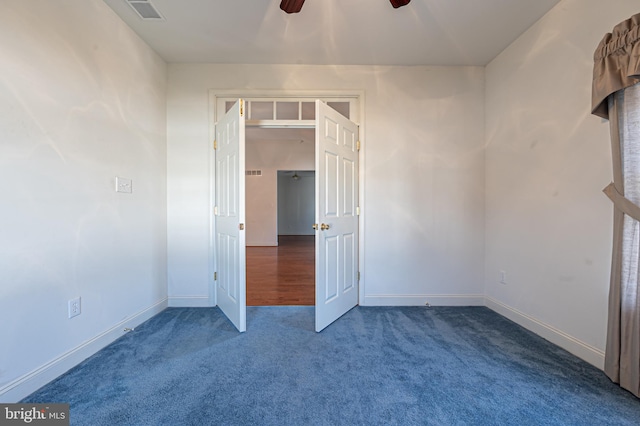 carpeted spare room featuring baseboards, visible vents, and ceiling fan