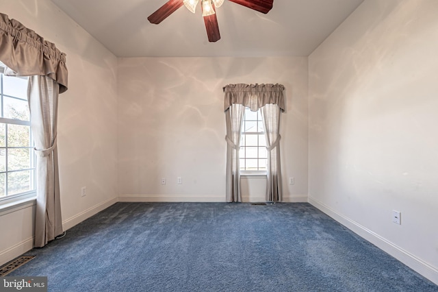 empty room with dark colored carpet, visible vents, and baseboards