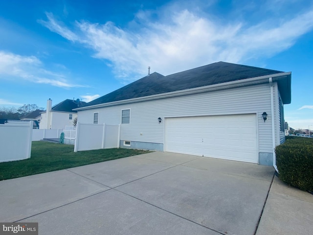 view of home's exterior featuring driveway, a lawn, an attached garage, and fence