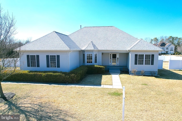 ranch-style home with roof with shingles, a front yard, and fence