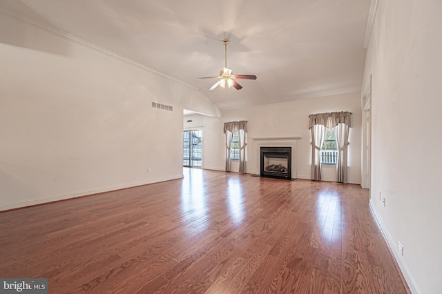 unfurnished living room with ceiling fan, wood finished floors, a fireplace with flush hearth, visible vents, and baseboards