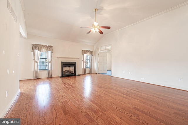 unfurnished living room featuring visible vents, a ceiling fan, a glass covered fireplace, wood finished floors, and baseboards