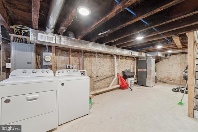 basement with electric panel, heating unit, and washing machine and clothes dryer