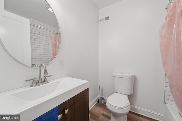 full bathroom with hardwood / wood-style floors, vanity, shower / bath combo, and toilet