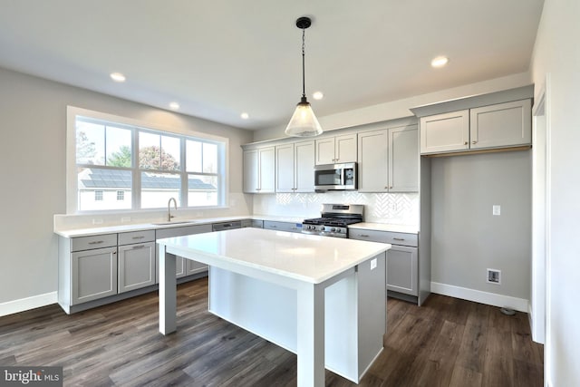 kitchen featuring sink, dark wood-type flooring, stainless steel appliances, decorative backsplash, and a kitchen island