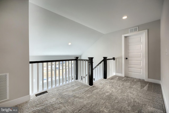 hallway with carpet flooring and vaulted ceiling