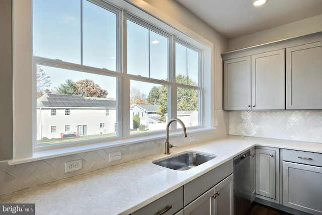 kitchen featuring backsplash, sink, stainless steel dishwasher, gray cabinets, and light stone countertops