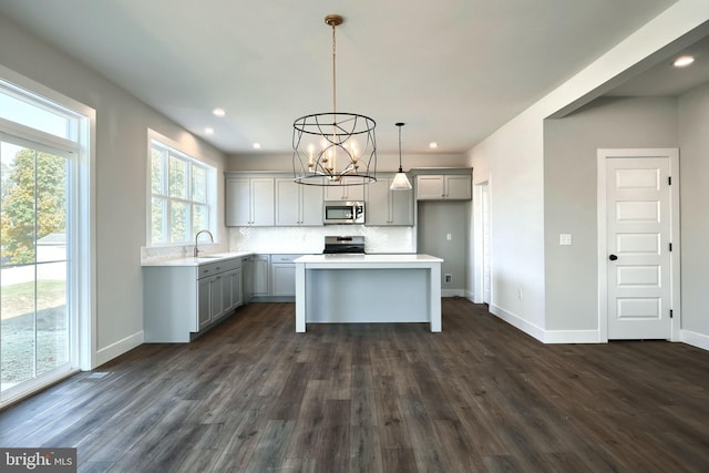 kitchen featuring gray cabinetry, sink, hanging light fixtures, dark hardwood / wood-style floors, and stainless steel appliances