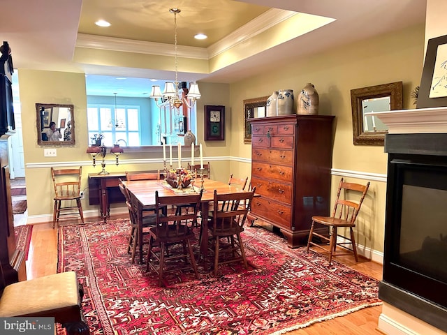 dining space with a chandelier, a tray ceiling, hardwood / wood-style flooring, and crown molding