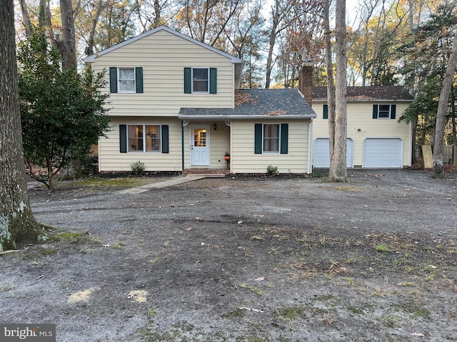 view of front of house with roof with shingles, driveway, a chimney, and an attached garage