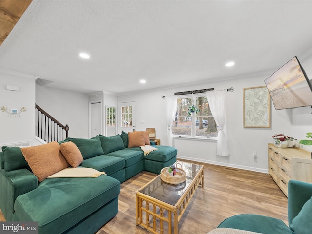 living area with wood finished floors, crown molding, baseboards, and stairs