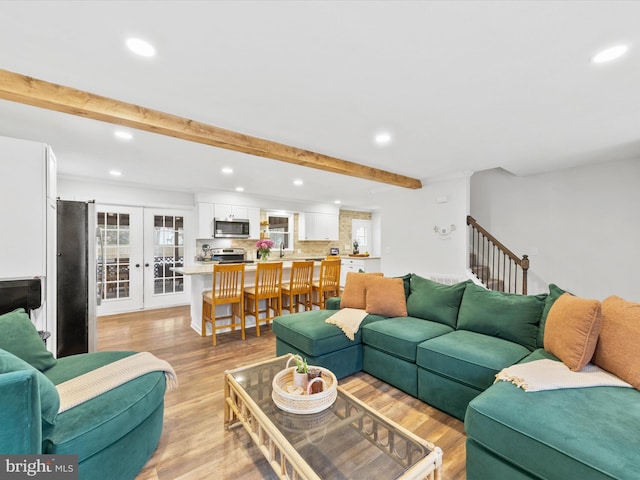 living area featuring light wood-type flooring, recessed lighting, beam ceiling, and french doors