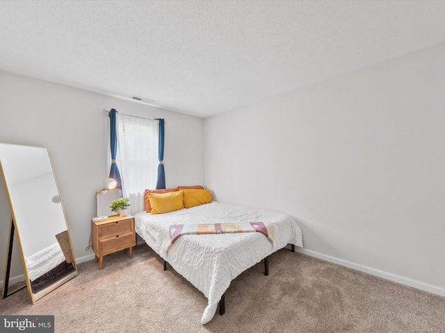 bedroom with a textured ceiling, carpet floors, visible vents, and baseboards