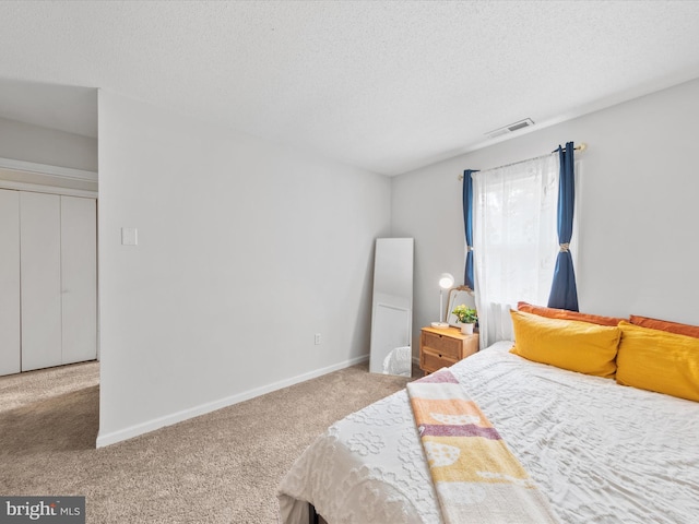 carpeted bedroom with visible vents, a textured ceiling, and baseboards