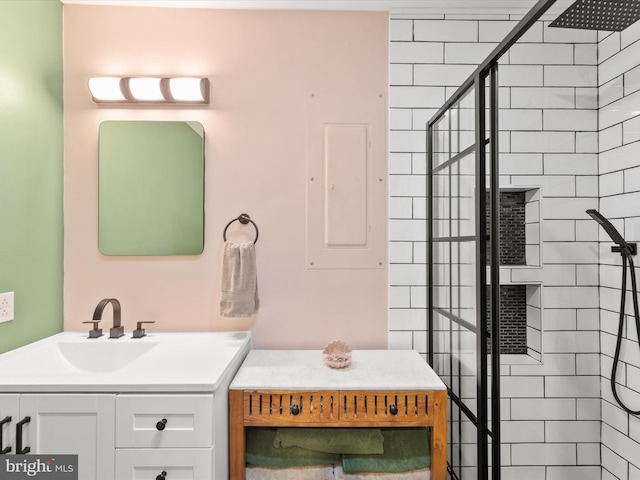 full bath featuring tiled shower and vanity