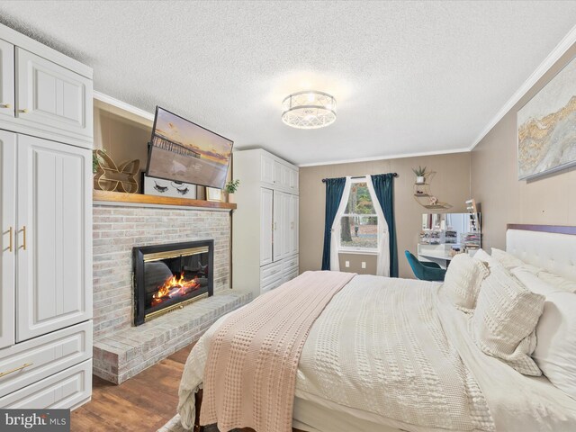 bedroom featuring dark wood-style floors, a textured ceiling, a fireplace, and crown molding