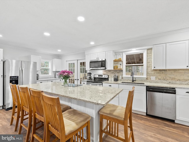 kitchen with appliances with stainless steel finishes, white cabinetry, a sink, and a kitchen island