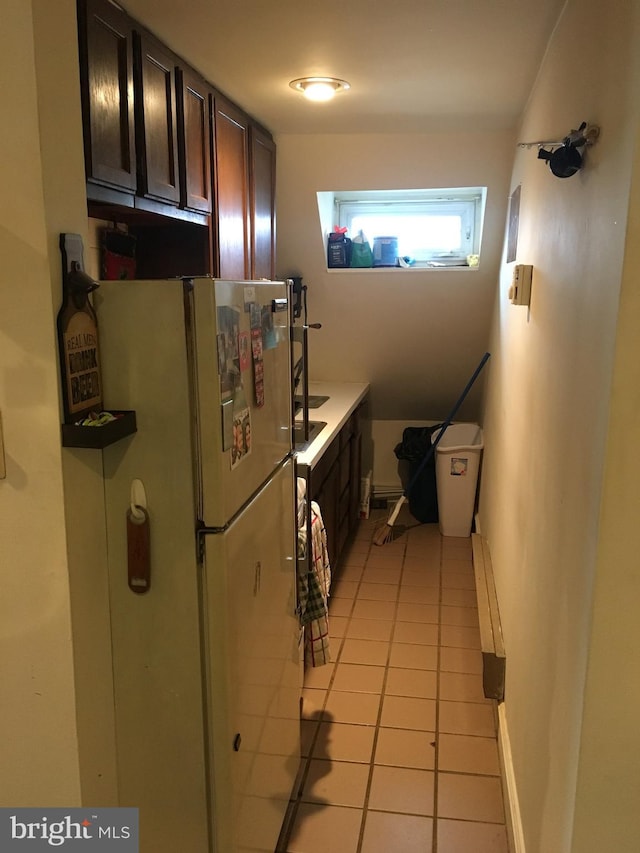 kitchen with dark brown cabinets, white fridge, and light tile patterned floors