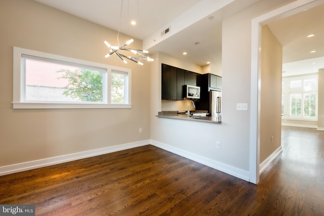 kitchen with kitchen peninsula, a wealth of natural light, dark wood-type flooring, and stainless steel appliances