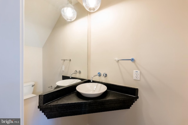 bathroom featuring toilet, sink, and vaulted ceiling