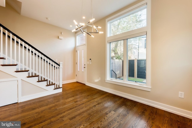 foyer with dark hardwood / wood-style flooring, a towering ceiling, and a chandelier