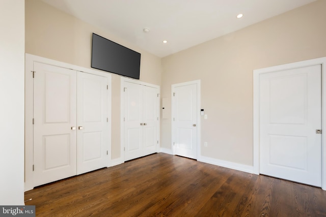 unfurnished bedroom with dark wood-type flooring and multiple closets