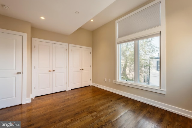 unfurnished bedroom with two closets and dark hardwood / wood-style floors