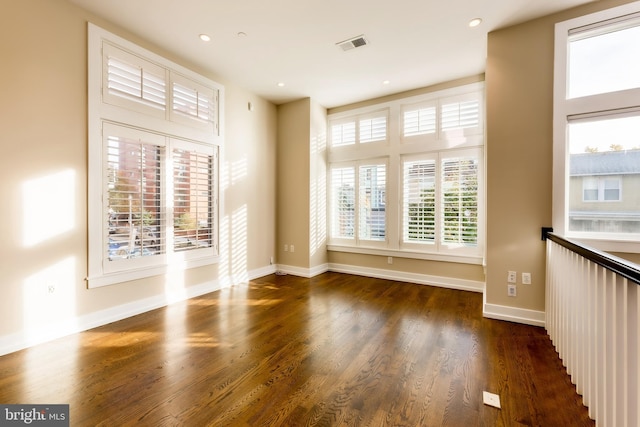 empty room with plenty of natural light and dark hardwood / wood-style flooring