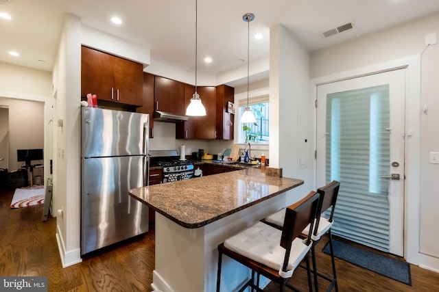 kitchen with hanging light fixtures, stainless steel appliances, dark hardwood / wood-style flooring, kitchen peninsula, and a breakfast bar