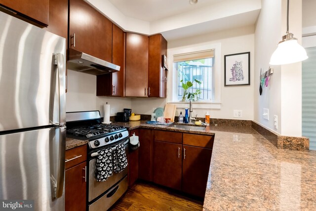 kitchen featuring sink, dark hardwood / wood-style flooring, extractor fan, decorative light fixtures, and appliances with stainless steel finishes