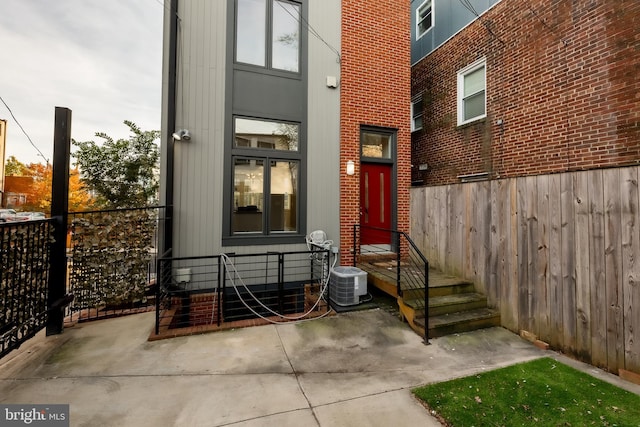 view of exterior entry with a patio and central AC