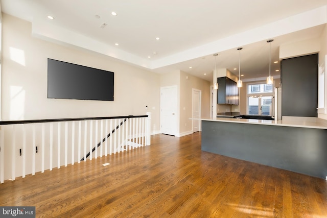 kitchen with kitchen peninsula, hanging light fixtures, and dark wood-type flooring