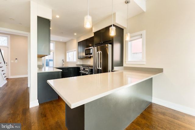 kitchen featuring stainless steel appliances, kitchen peninsula, pendant lighting, and dark hardwood / wood-style floors