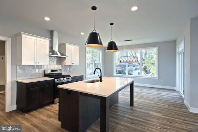 kitchen with stainless steel gas range oven, white cabinets, wall chimney exhaust hood, and a wealth of natural light