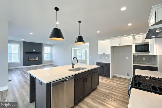 kitchen featuring white cabinets, appliances with stainless steel finishes, an island with sink, and sink